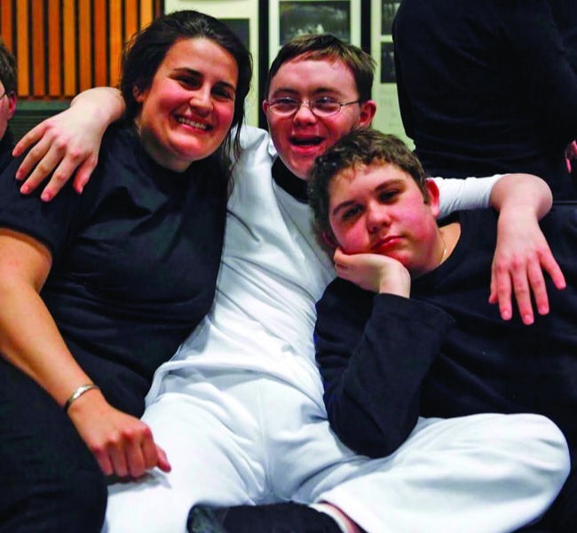 Three people sitting on the floor, one wearing glasses, engaged in conversation and enjoying each other's company. Three people sitting on the floor, one wearing glasses, engaged in conversation and enjoying each other's company.
